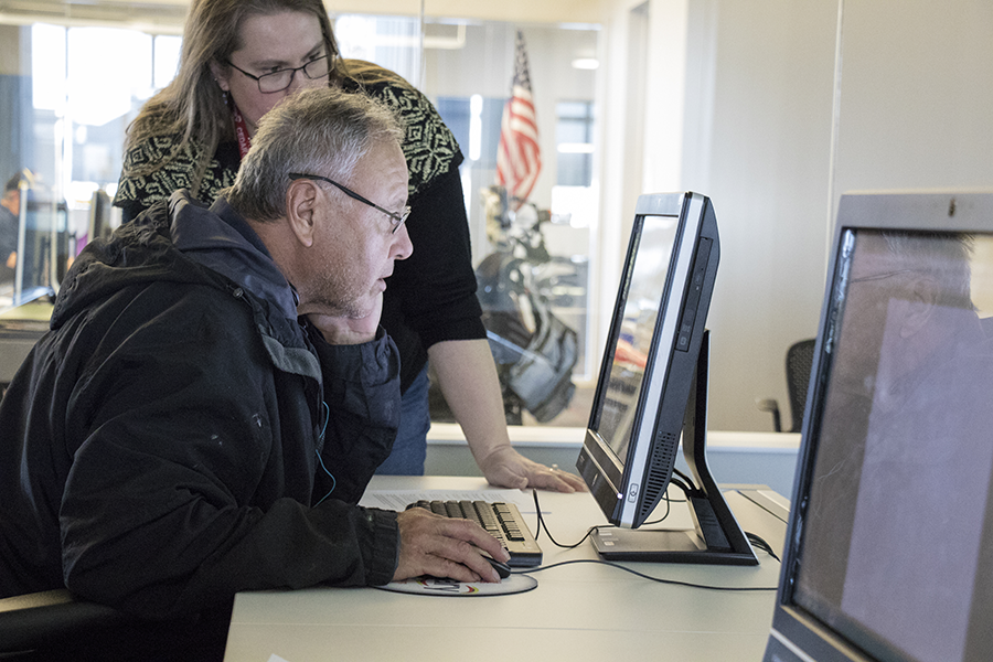 Librarian helping man on desktop computer