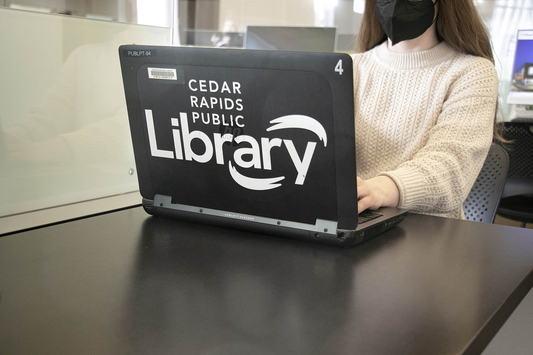 Library laptop on a table with woman in a mask 
