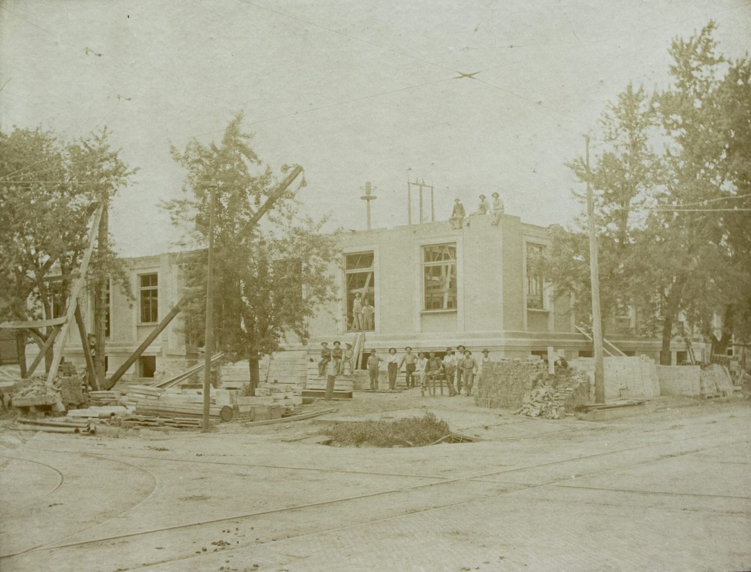 Workers stand in front of a partially-finished building in this black and white photo.