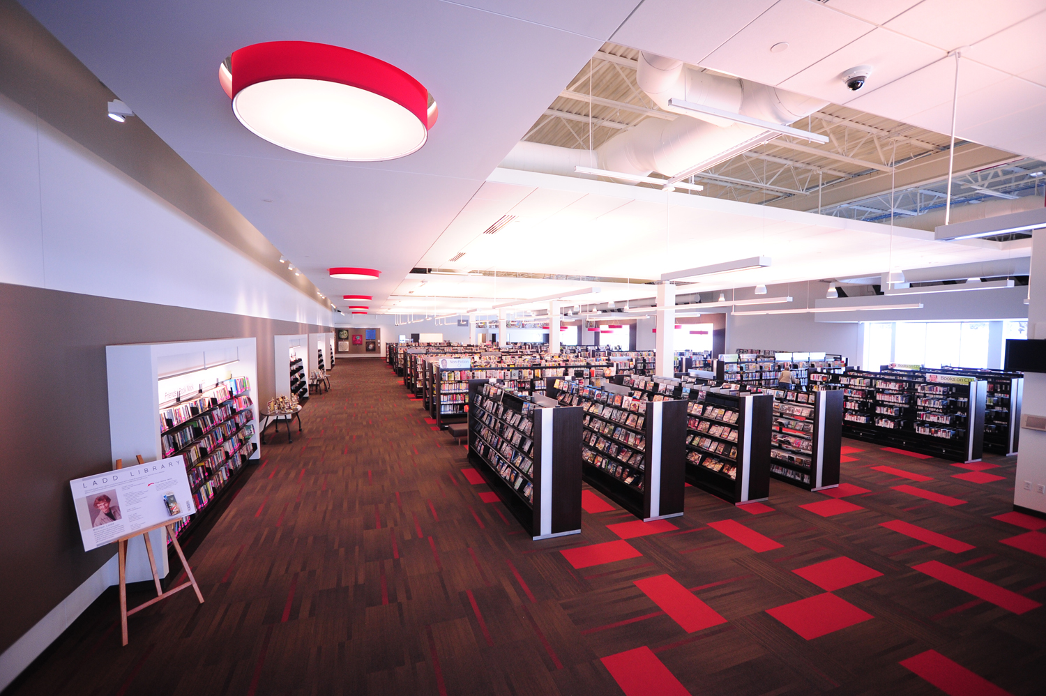 A red light fixture shines on rows of book shelves.