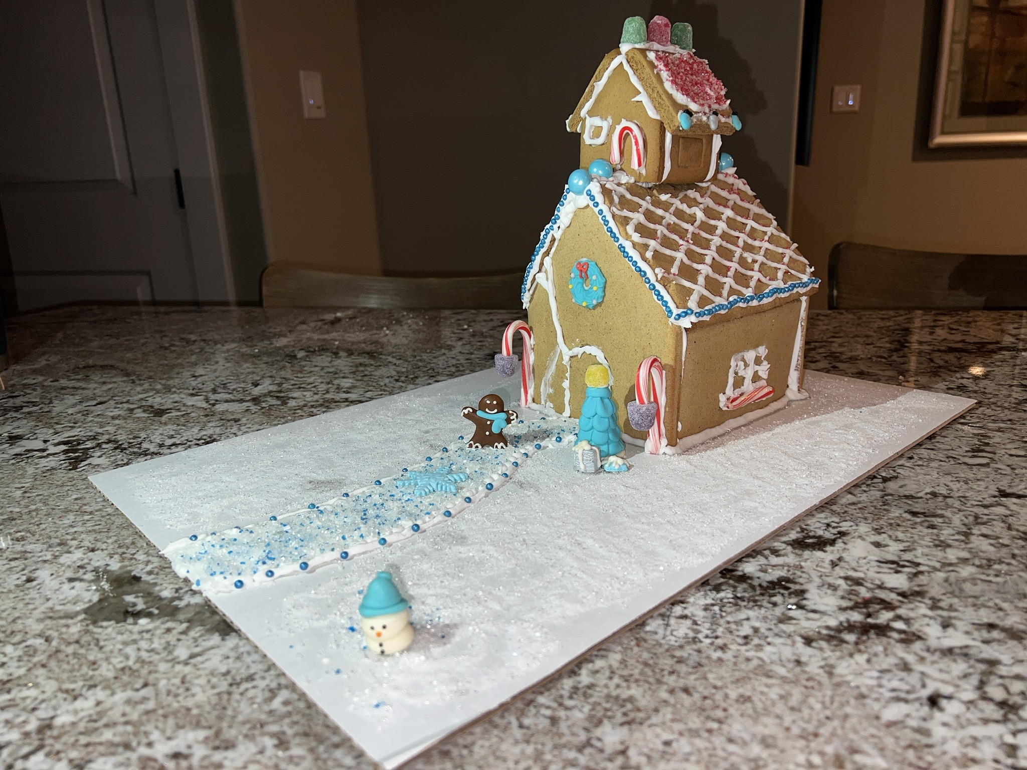 A gingerbread house has an ADU sitting on its roof.