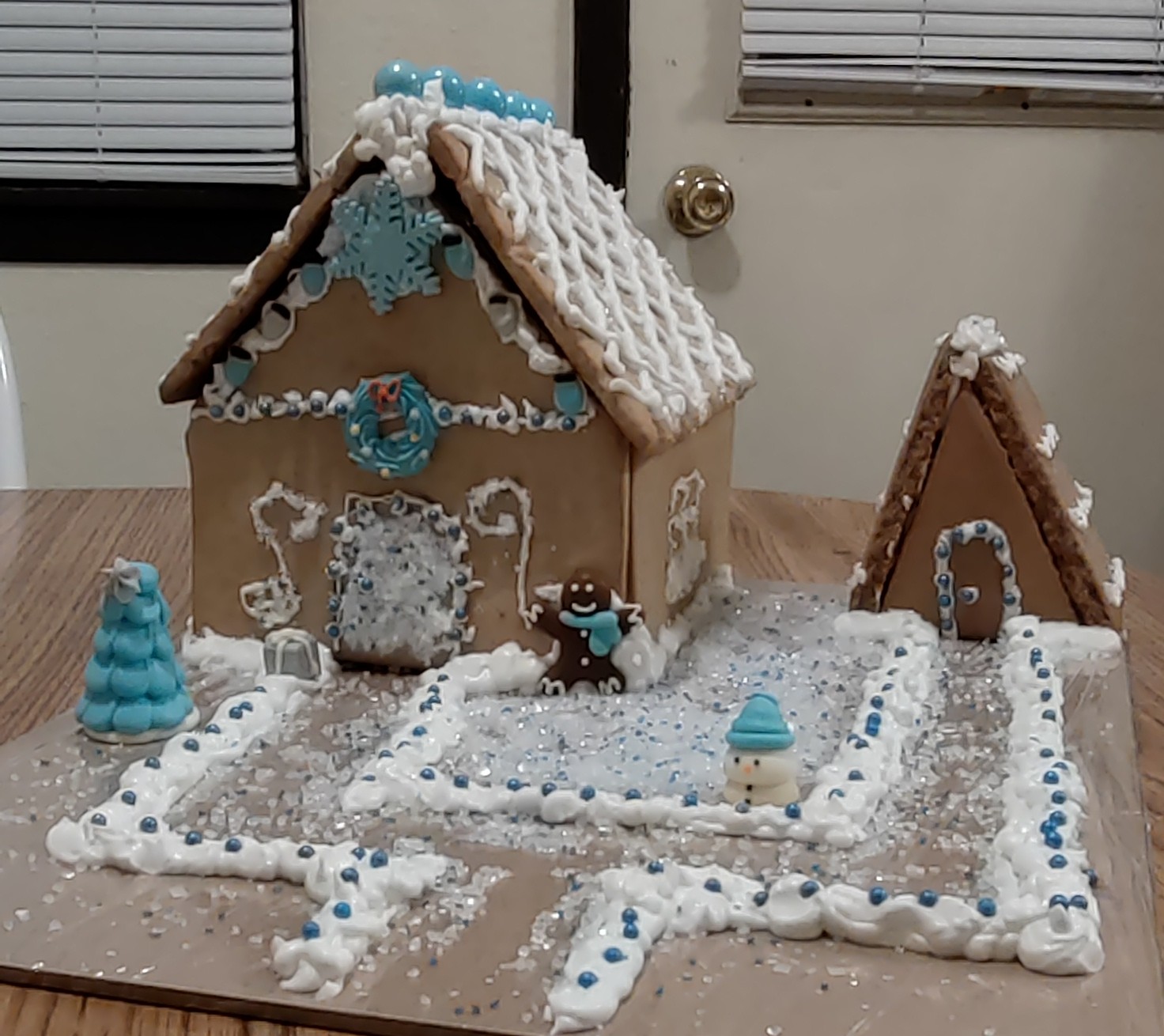 A gingerbread house with white icing on the roof and a white icing path to the ADU.