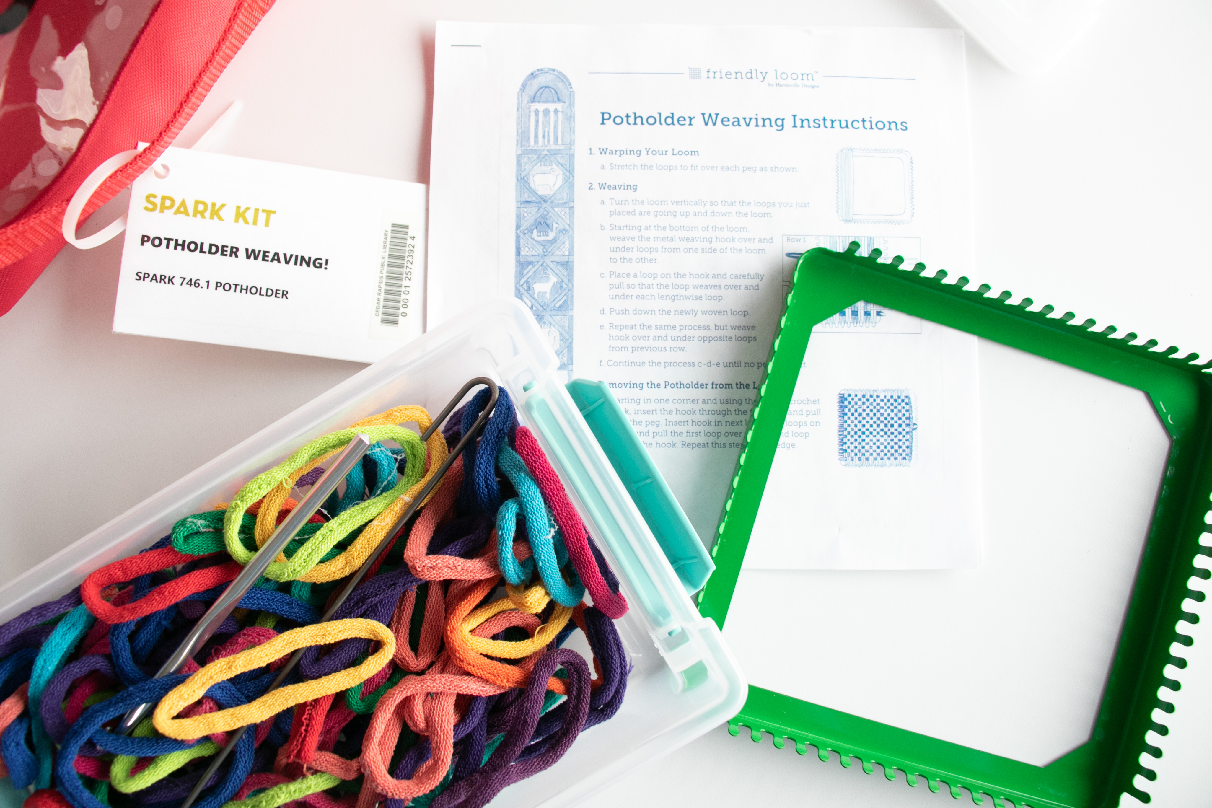 A box of colorful loops sits next to a square metal miniature loom.