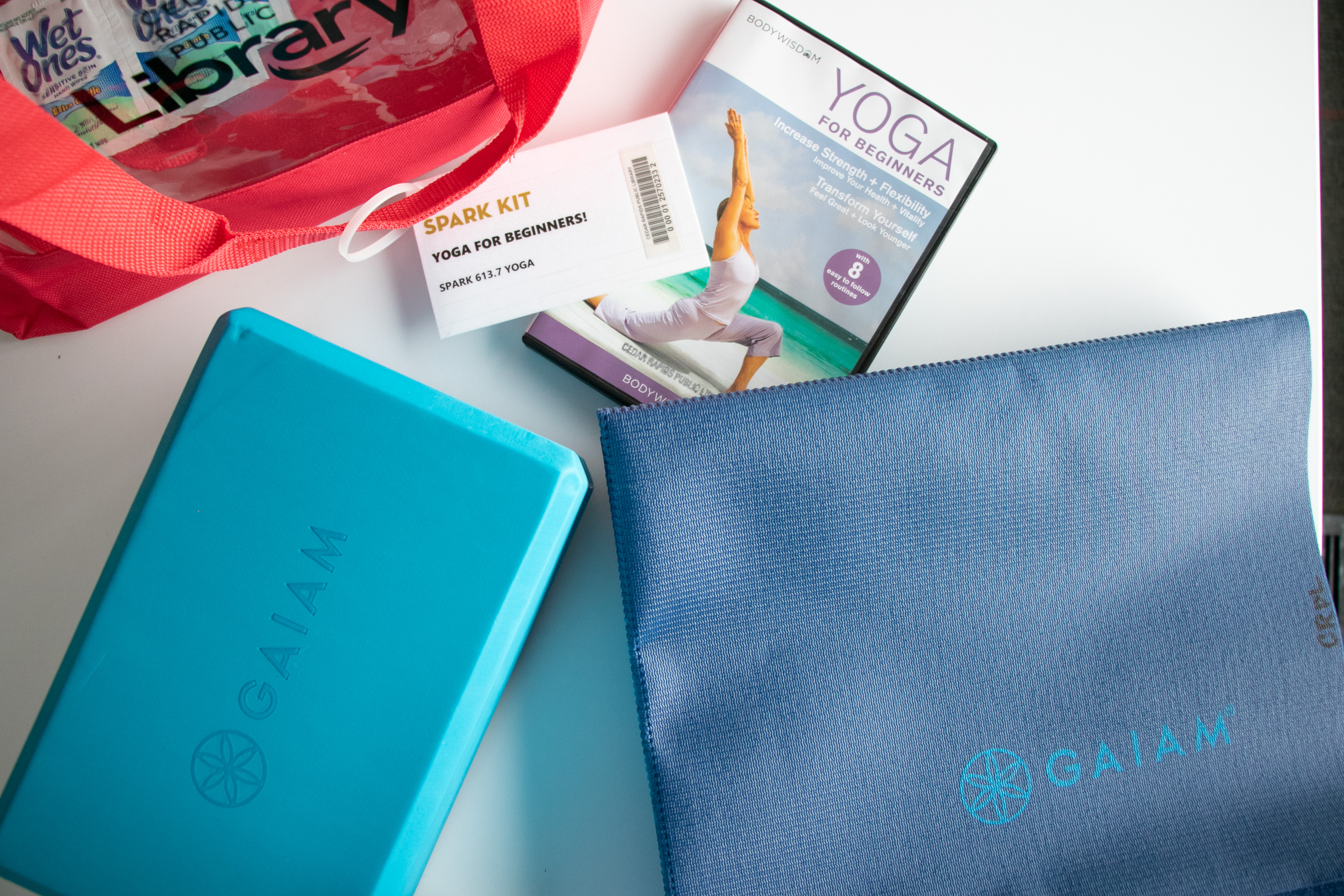 A blue yoga mat and yoga brick sit next to a yoga DVD.