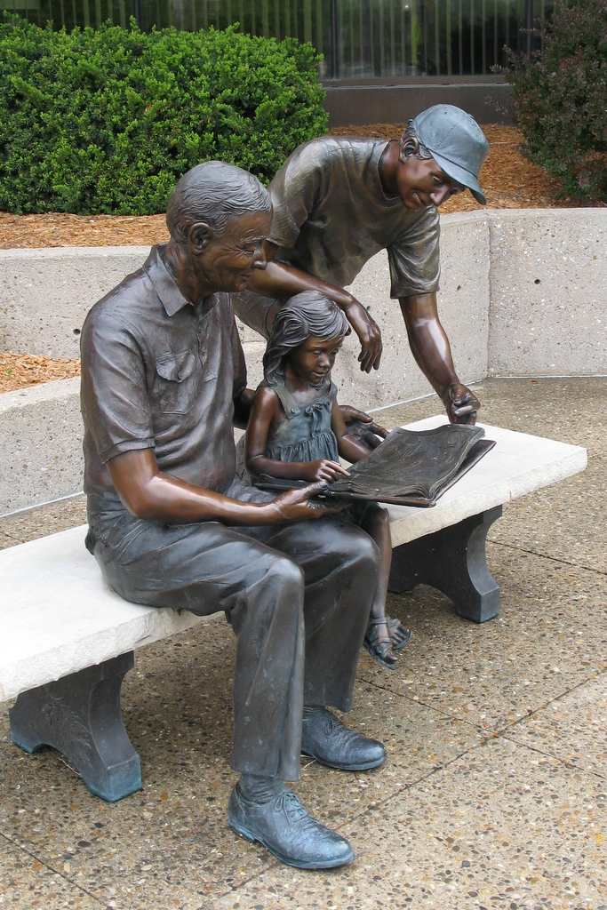 sculpture of three generations of people reading a book