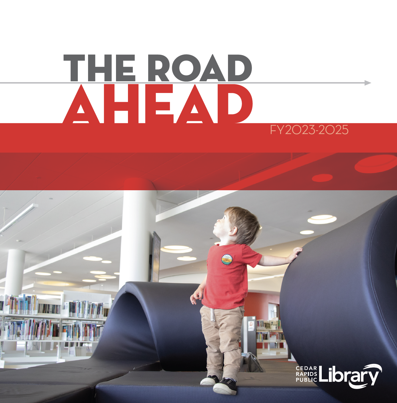 Little boy standing in children's library on curvy couch 