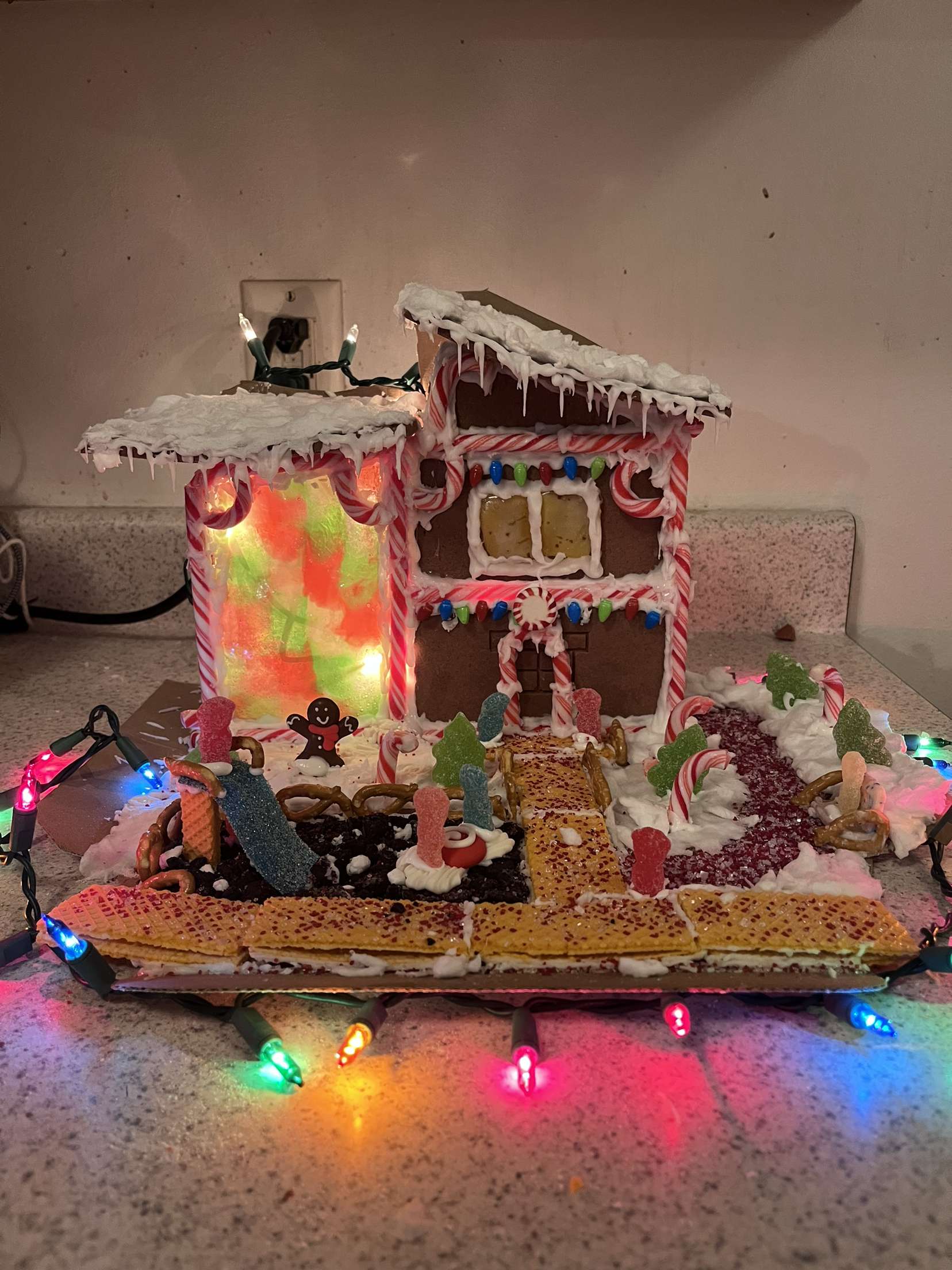 A gingerbread library is lit up with twinkle lights.