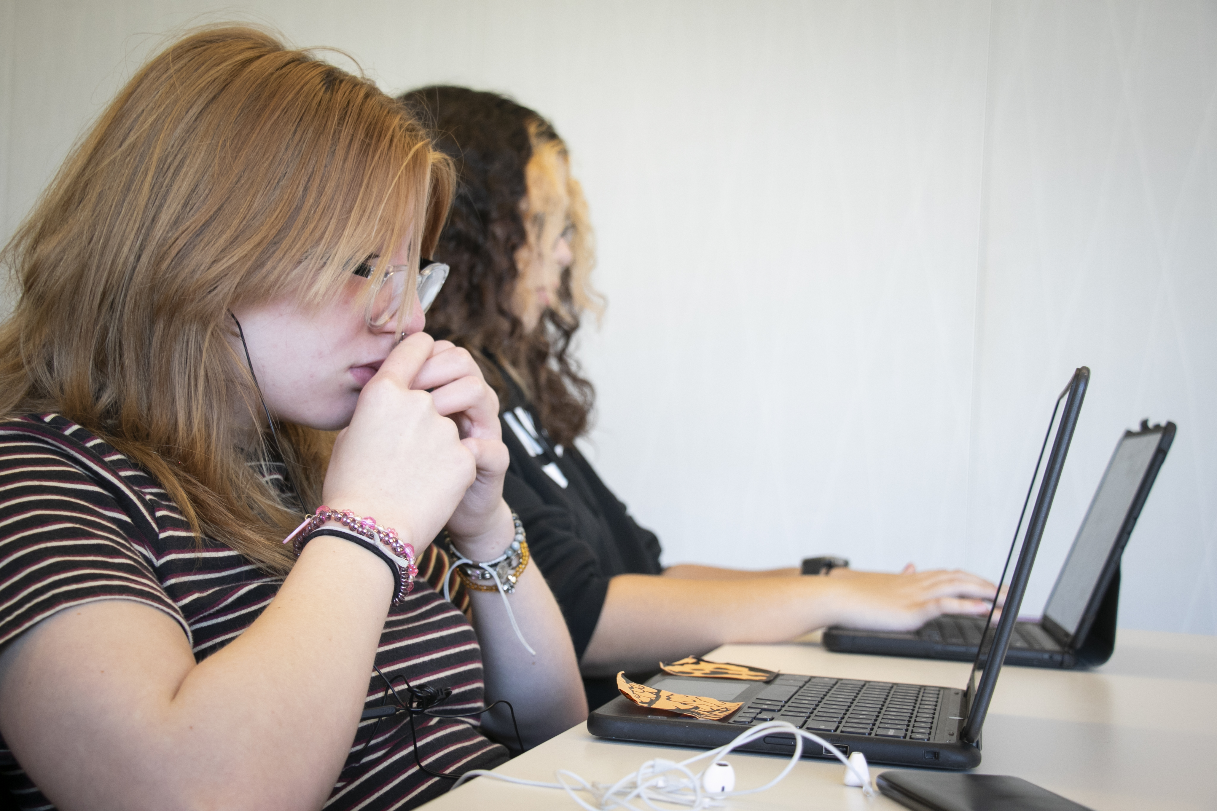 Teen girls look at laptops.