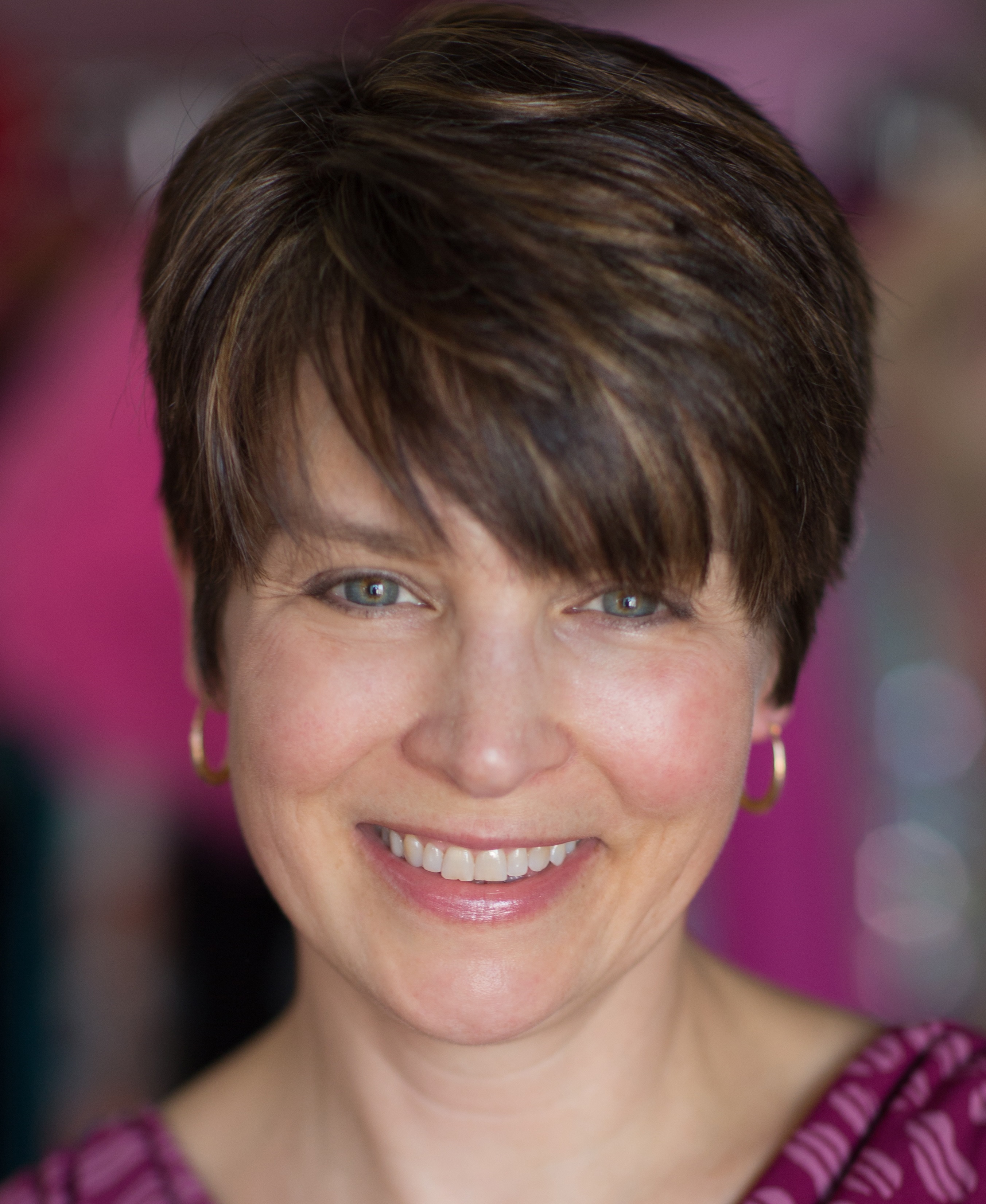 A woman with short hair smiles at the camera.