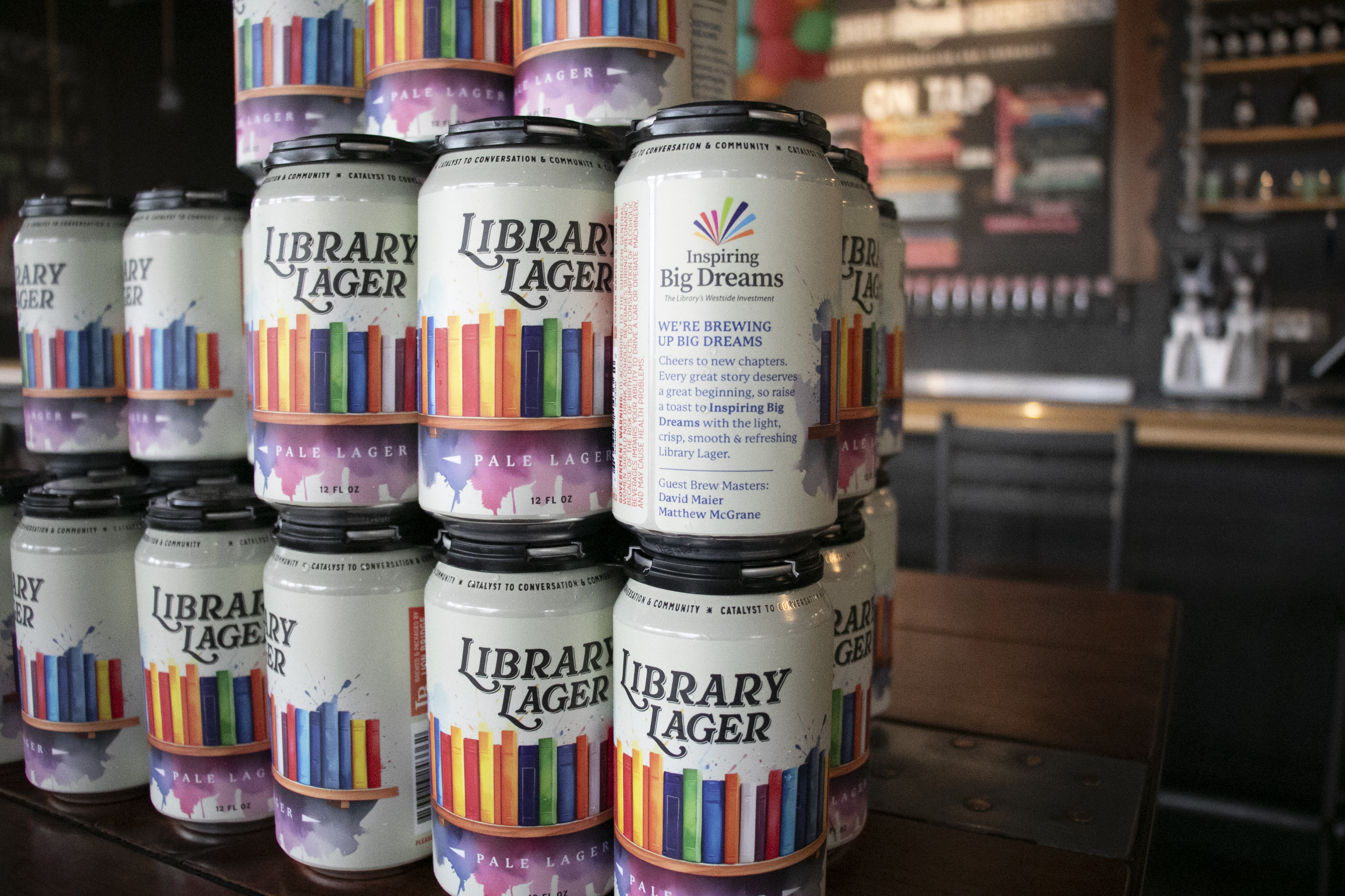 Cans of beer have a lable with book spines and the words "Library Lager."