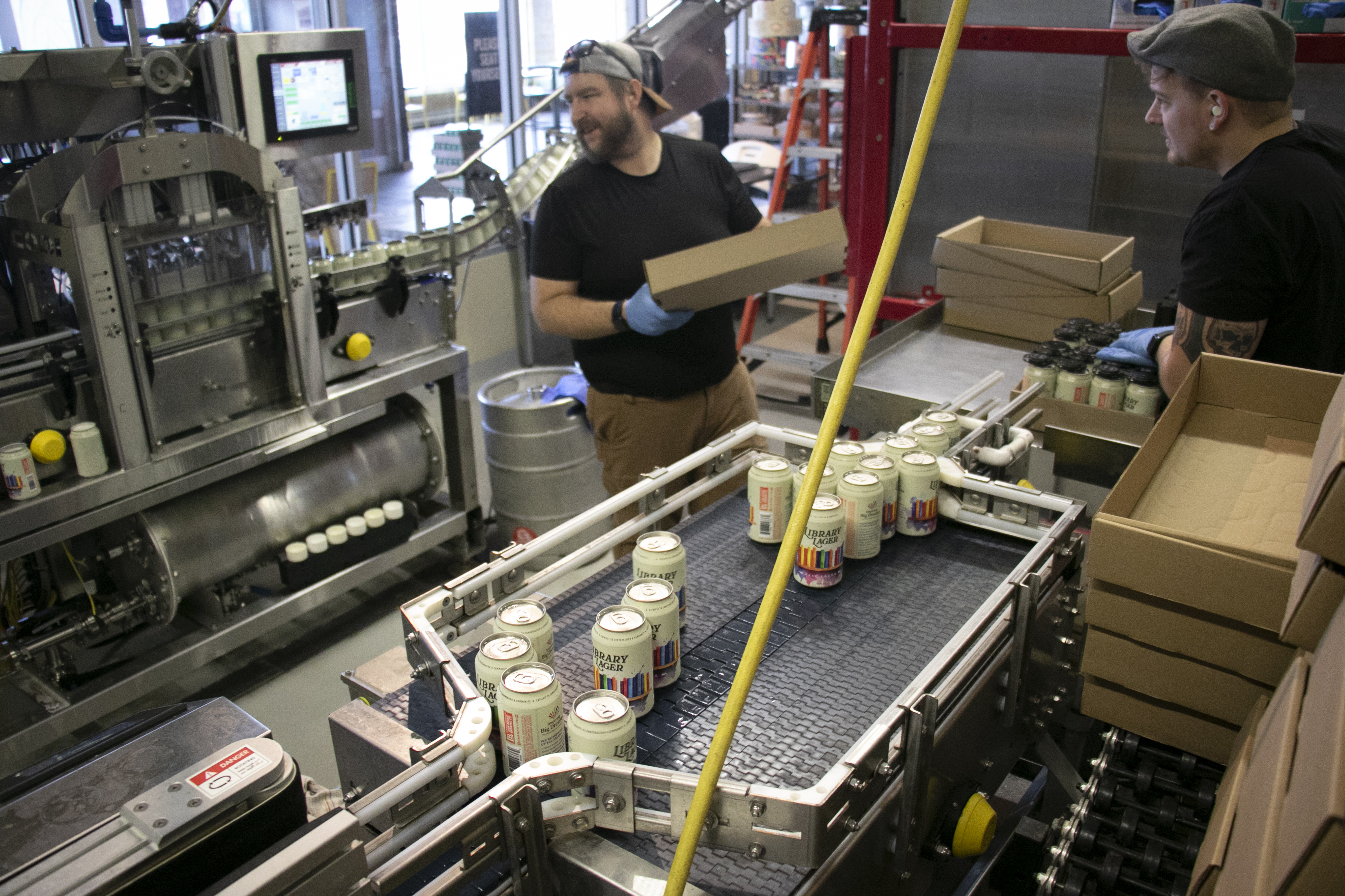 Lion Bridge staff process cans of Library Lager.