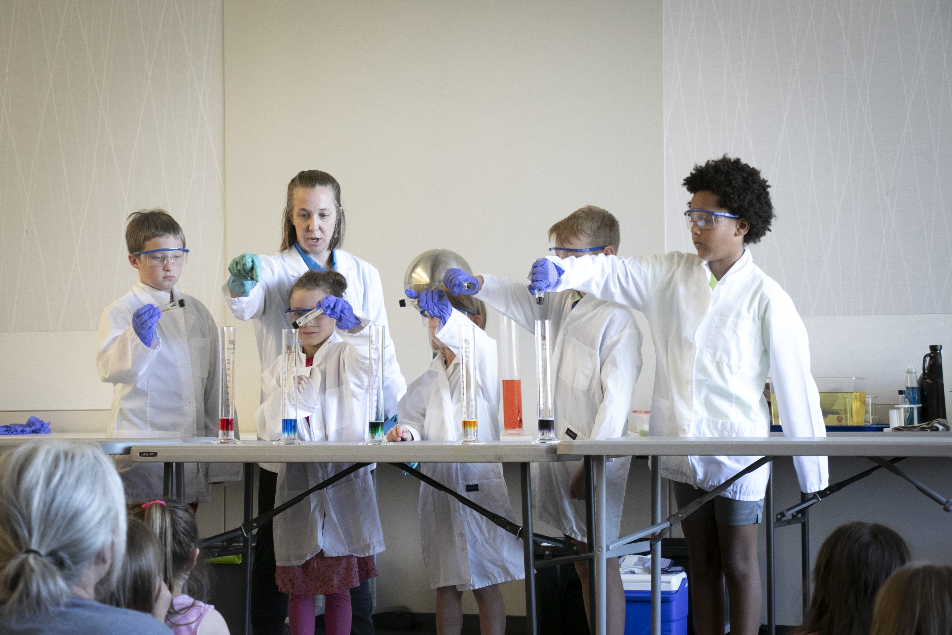 kids in lab coats pour chemicals into beakers