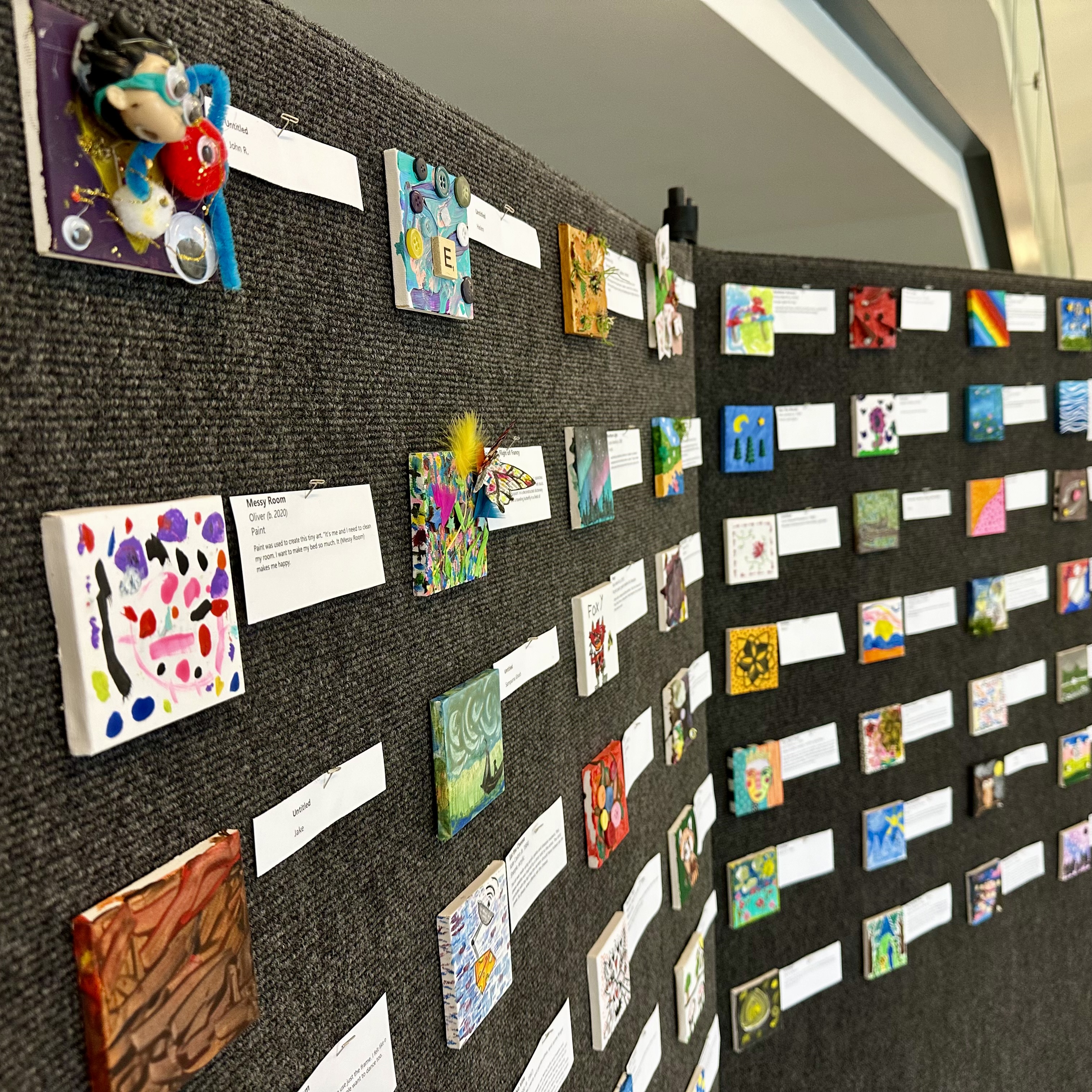 Walls are covered with Tiny Art canvases.