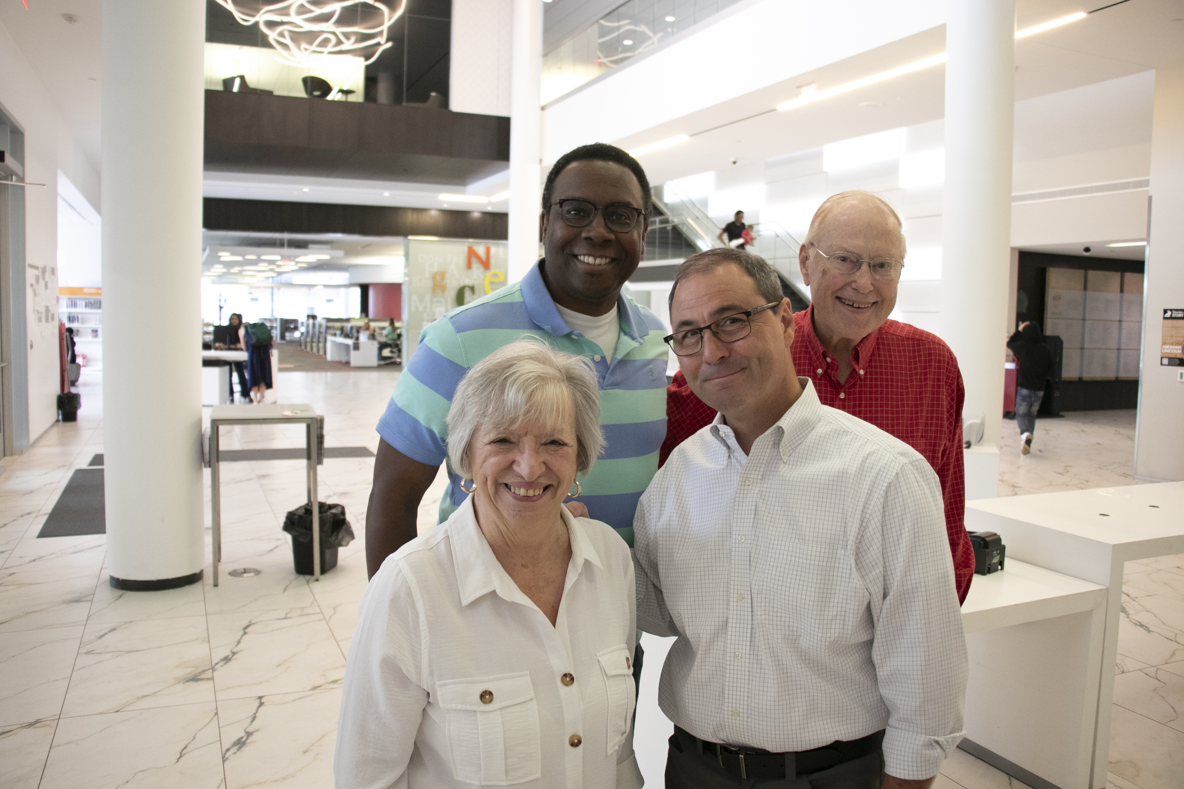 Four people smile in the Commons of the Downtown Library.