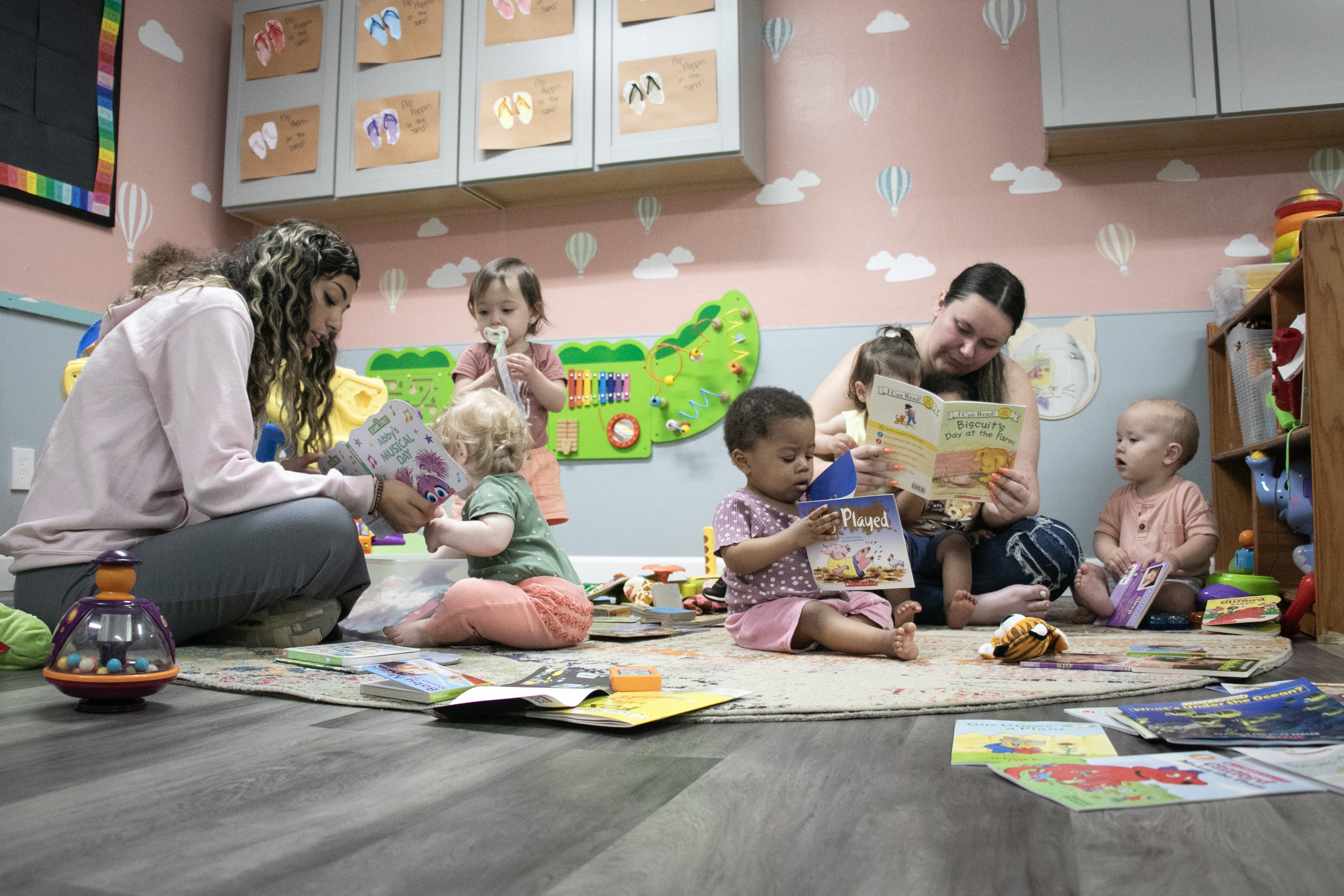 Children look at books with their daycare teachers.