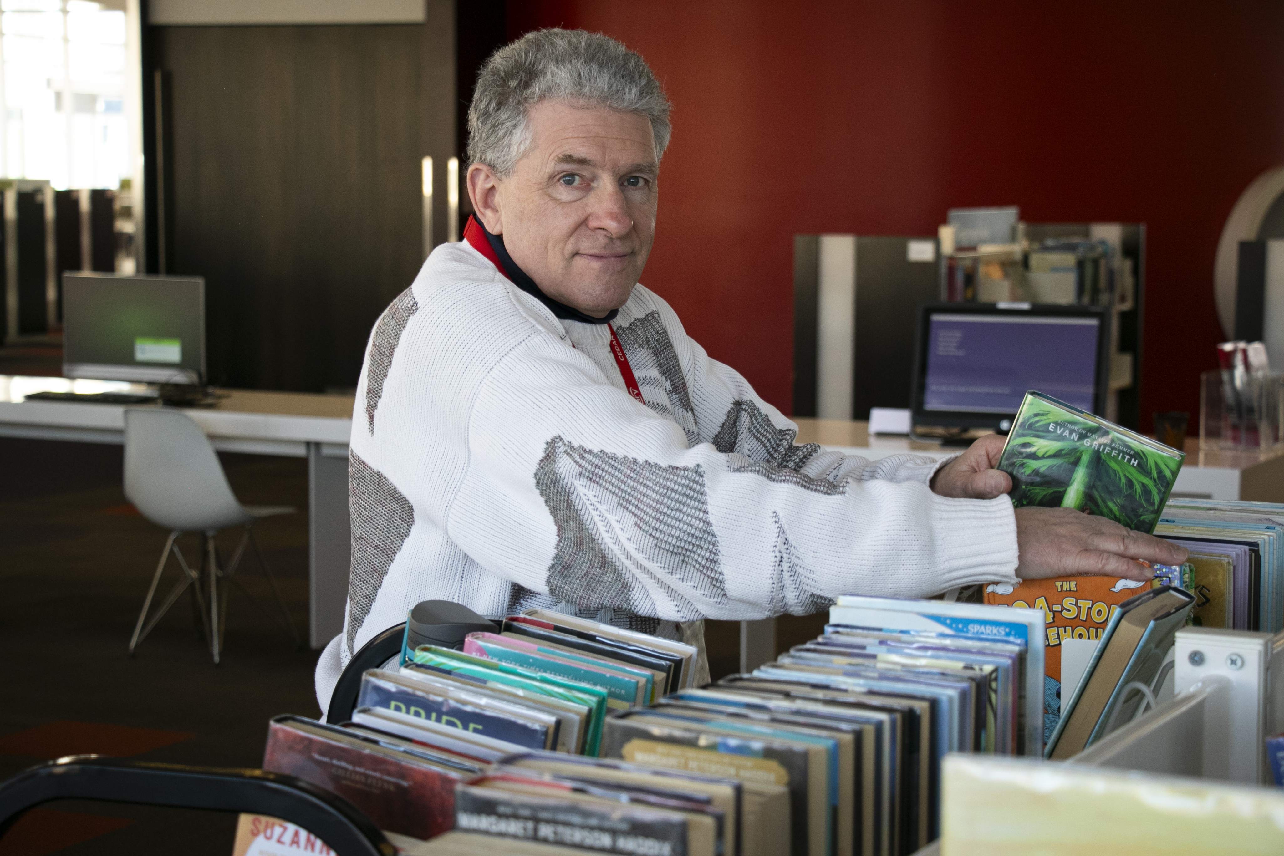 Curtis looks at the camera as he shelves books in the library.