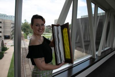 Artist in Residence Harper Folsom holding up an example of her work, a book she made