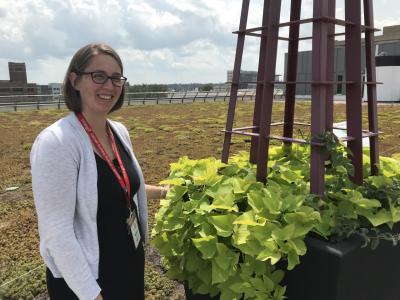 A woman with glasses stands by a planter on the library's roof.