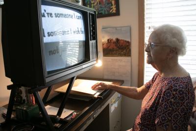 An older woman uses a screen magnifier to read.