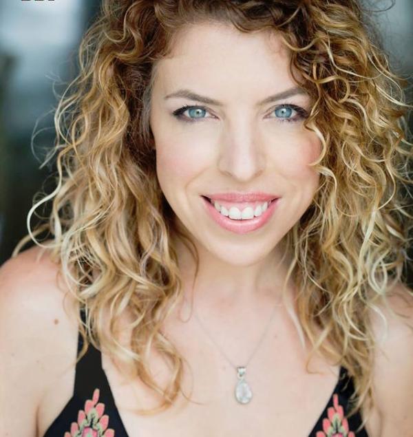 A woman with curly hair smiles.