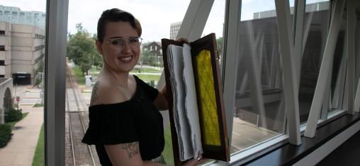 Artist in Residence Harper Folsom holding up an example of her work, a book she made 