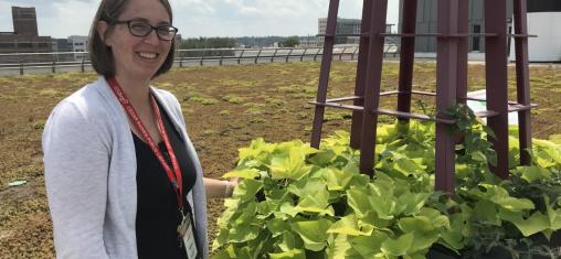 A woman with glasses stands by a planter on the library's roof.
