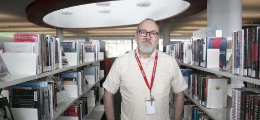 Wes Shirley wears a white shirt in front of book shelves.