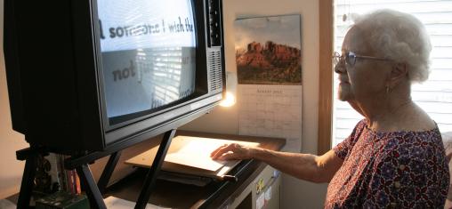 An older woman uses a screen magnifier to read.