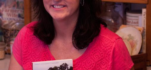 A woman holds up a copy of her book "A Culinary History of Iowa."