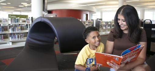 A boy smiles while his mom reads him "Horton Hears a Who."