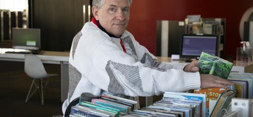 Curtis looks at the camera as he shelves books in the library.