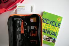 A bike repair kit with tools and a green book titled Bicycle Repair Manual.