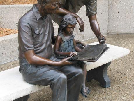 sculpture of three generations of people reading a book