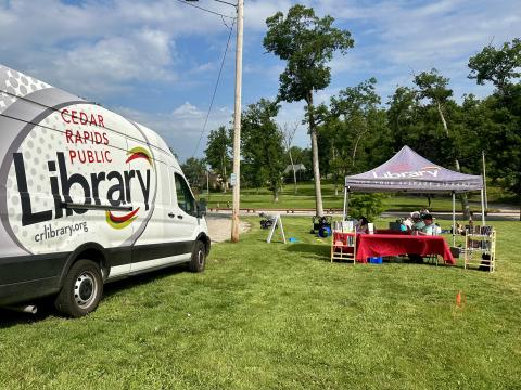 Library-branded van parked on grass next to a library-branded canopy tent