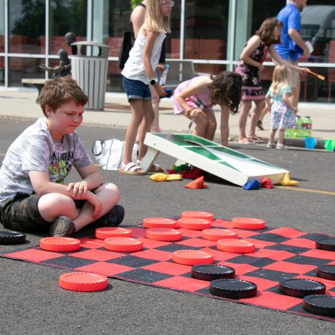 A boy looks at a giant checkers board.