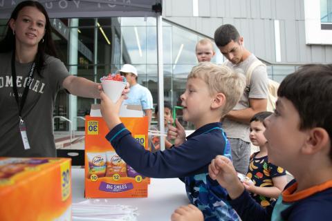 A boy accepts a snow cone from a woman outside the Downtown Library.