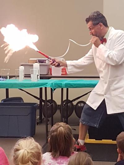 Man in lab coat blowing on tube creating ball of fire