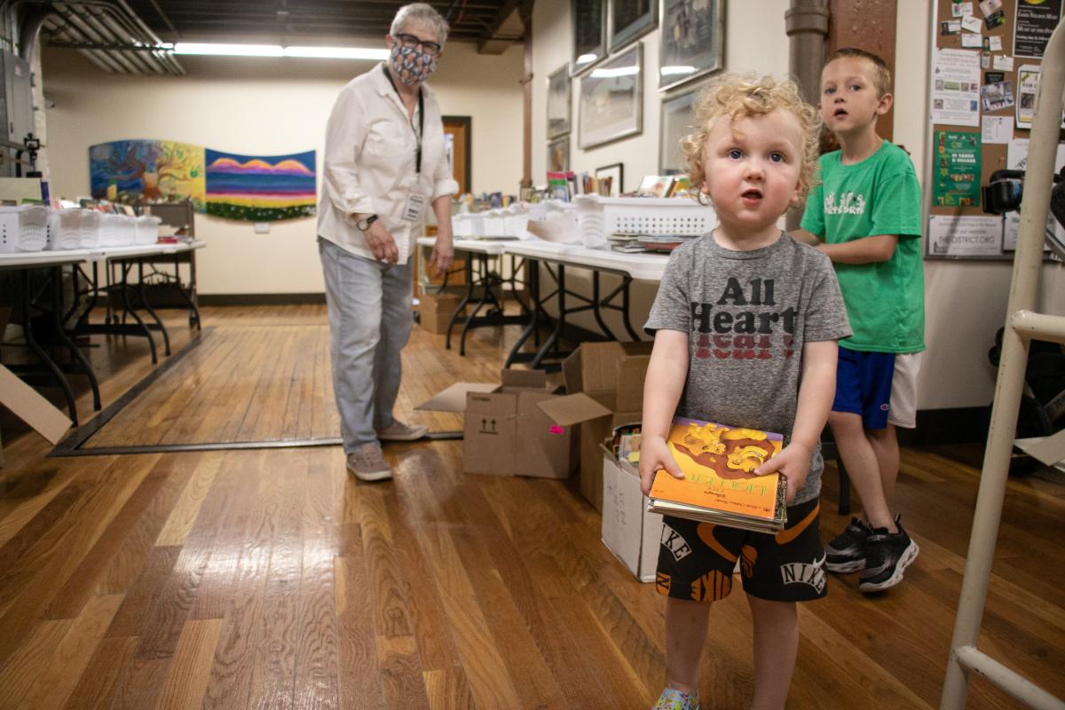 A book holds books in front of books on tables.