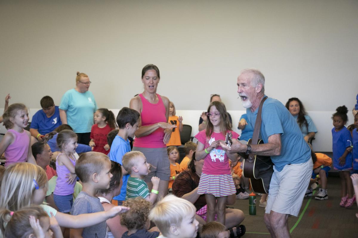 Tom Pease plays the guitar as children watch.