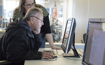 Librarian helping man on desktop computer