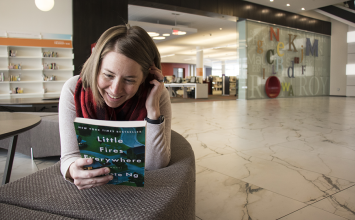 Woman holding book title "Little Fires Everywhere" while in the library
