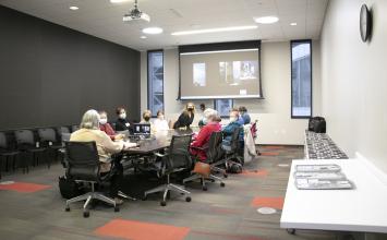 Women sit around a table in a conference room.