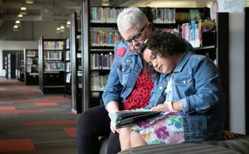 Grandmother and granddaughter reading together while sitting at Ladd Library