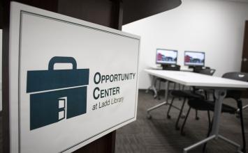 A sign says "Opportunity Center" in front of a table and computers.